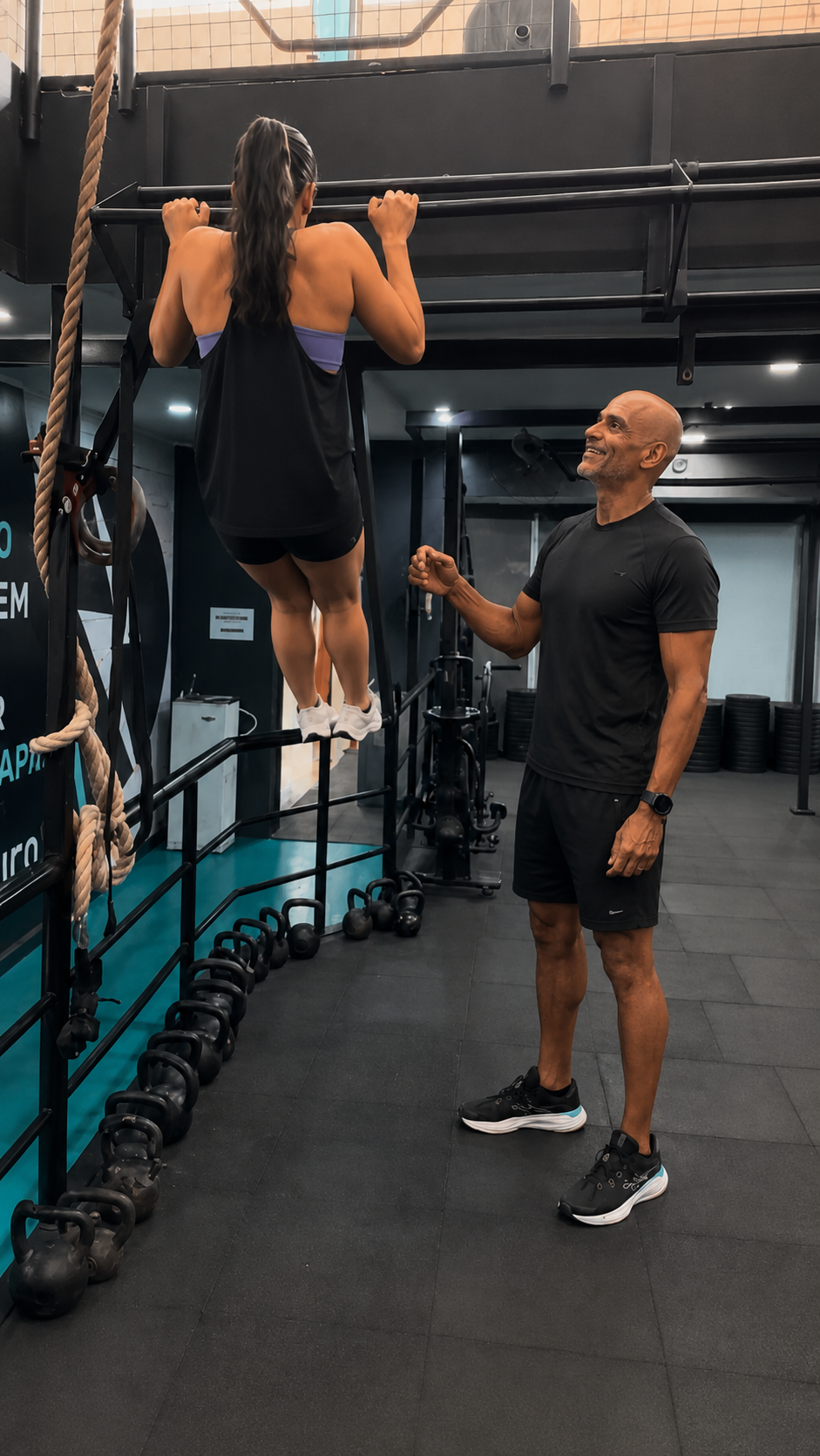 Victor Guilherme acompanhando de perto uma aluna durante exercício de barra, com orientação técnica e incentivo.